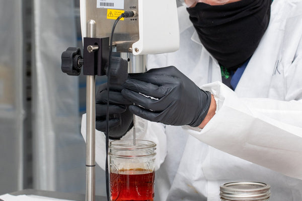 Lab technician in protective gear processing botanical extract samples