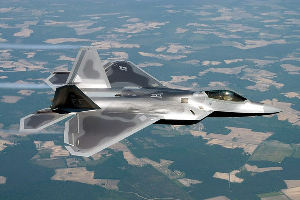 F-22 Raptor military aircraft in flight over countryside