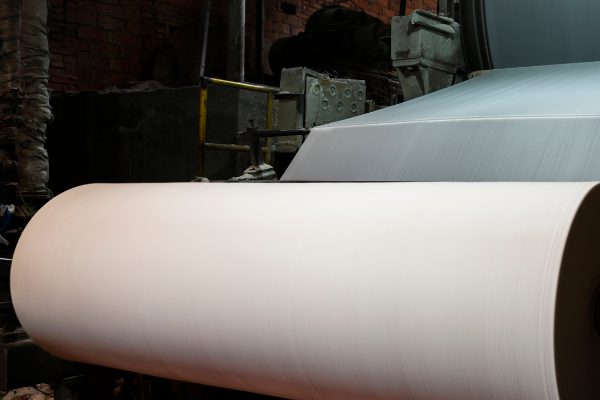 Large paper roll on industrial paper mill production floor