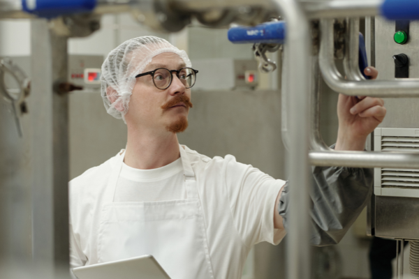 Food processing technician operating stainless steel equipment in sanitary facility