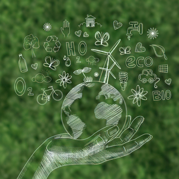 Hand holding a green-toned globe surrounded by sustainability icons — eco, recycling, wind, water, bicycle