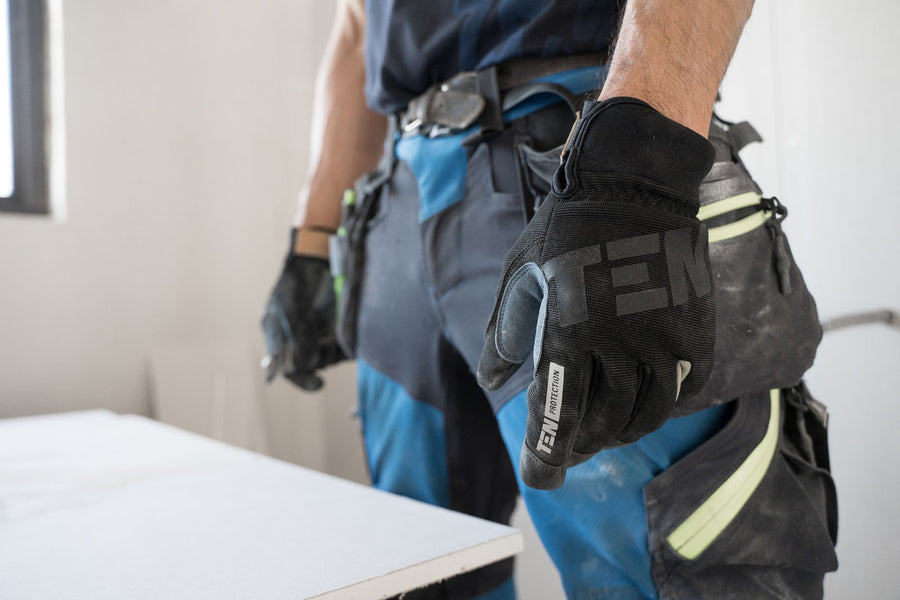 Close-up of a construction worker wearing safety gloves indoors, focused on hand protection.