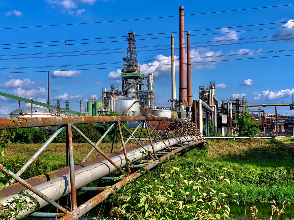 Rusty pipes and structures of an industrial refinery under a vibrant blue sky in Karlsruhe, Germany.