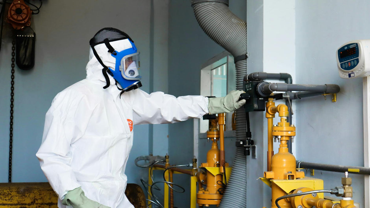 Industrial worker in protective gear inspecting machinery for safety compliance in Indonesia.