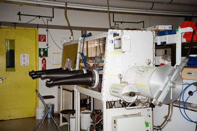 An industrial laboratory setup featuring a glove box with safety equipment.
