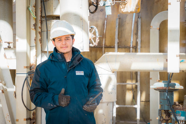 Engineer in safety gear within an industrial setting in Libya, pipes and machinery visible.