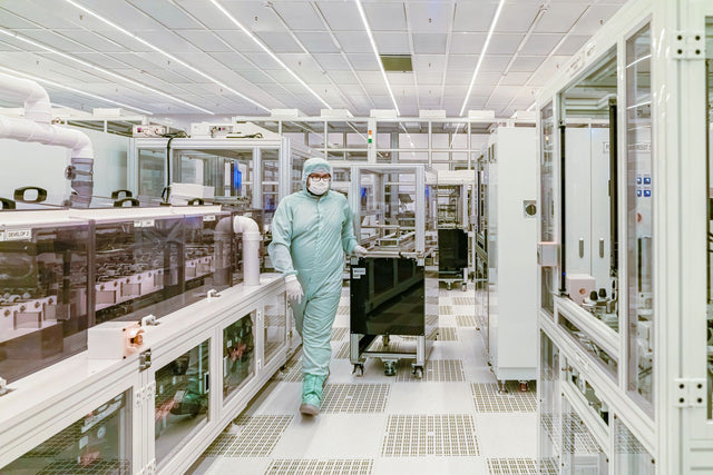 Scientist in protective gear walking in a high-tech cleanroom laboratory environment.