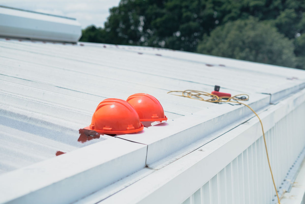 Red hard hats and safety equipment on a metal roof, emphasizing construction safety.