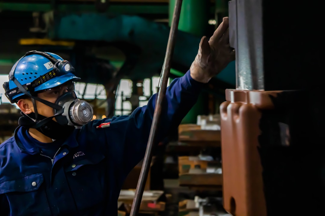 man in blue jacket holding gray metal pipe