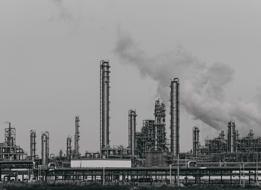a black and white photo of a factory with smoke stacks