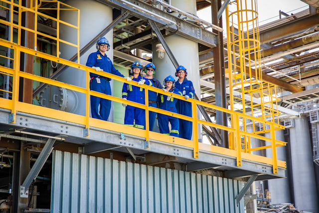 Workers stand on a platform in an industrial plant.