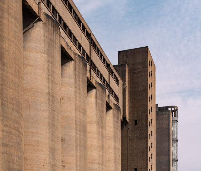 Tall concrete industrial silos against a cloudy sky