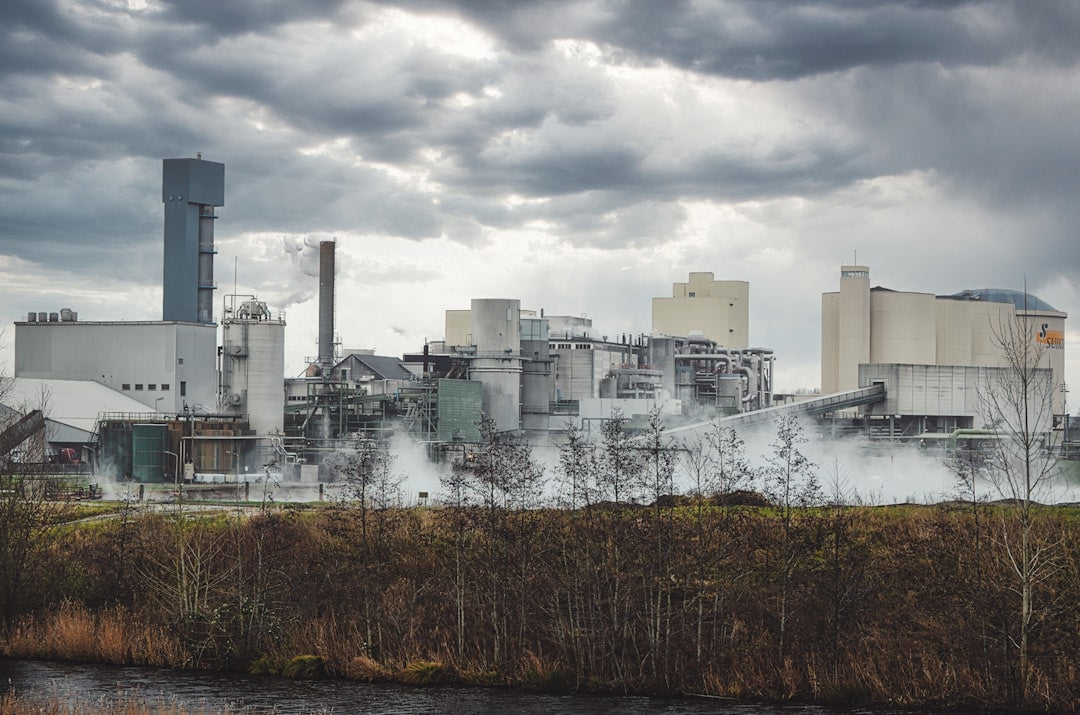 Industrial factory with steam rising under cloudy sky