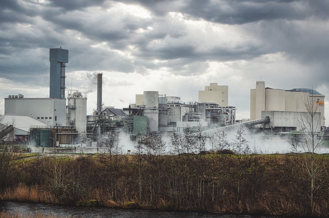 Industrial factory with steam rising under cloudy sky