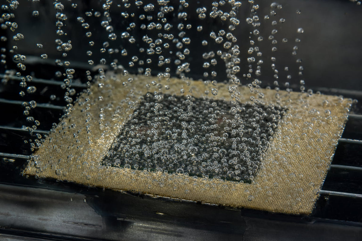 Nucleate boiling on a processor package submerged in clear dielectric fluid, vapor bubbles streaming upward from the chip surface.