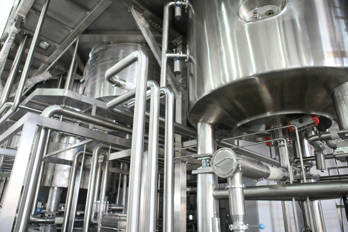 Stainless-steel process tanks and sanitary piping on a steel platform in an industrial plant