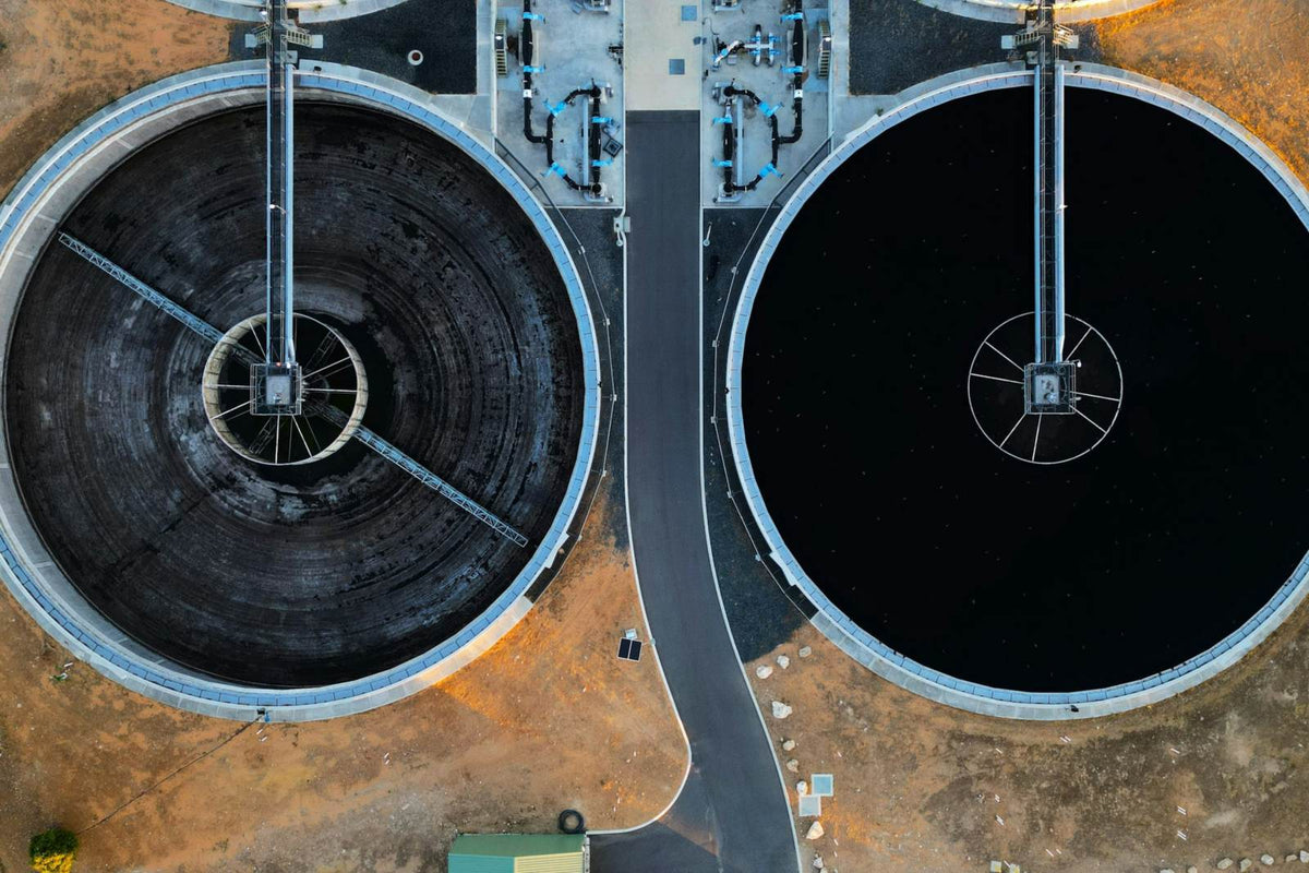 Aerial view of two circular clarifier basins with bridge walkways at a wastewater treatment plant